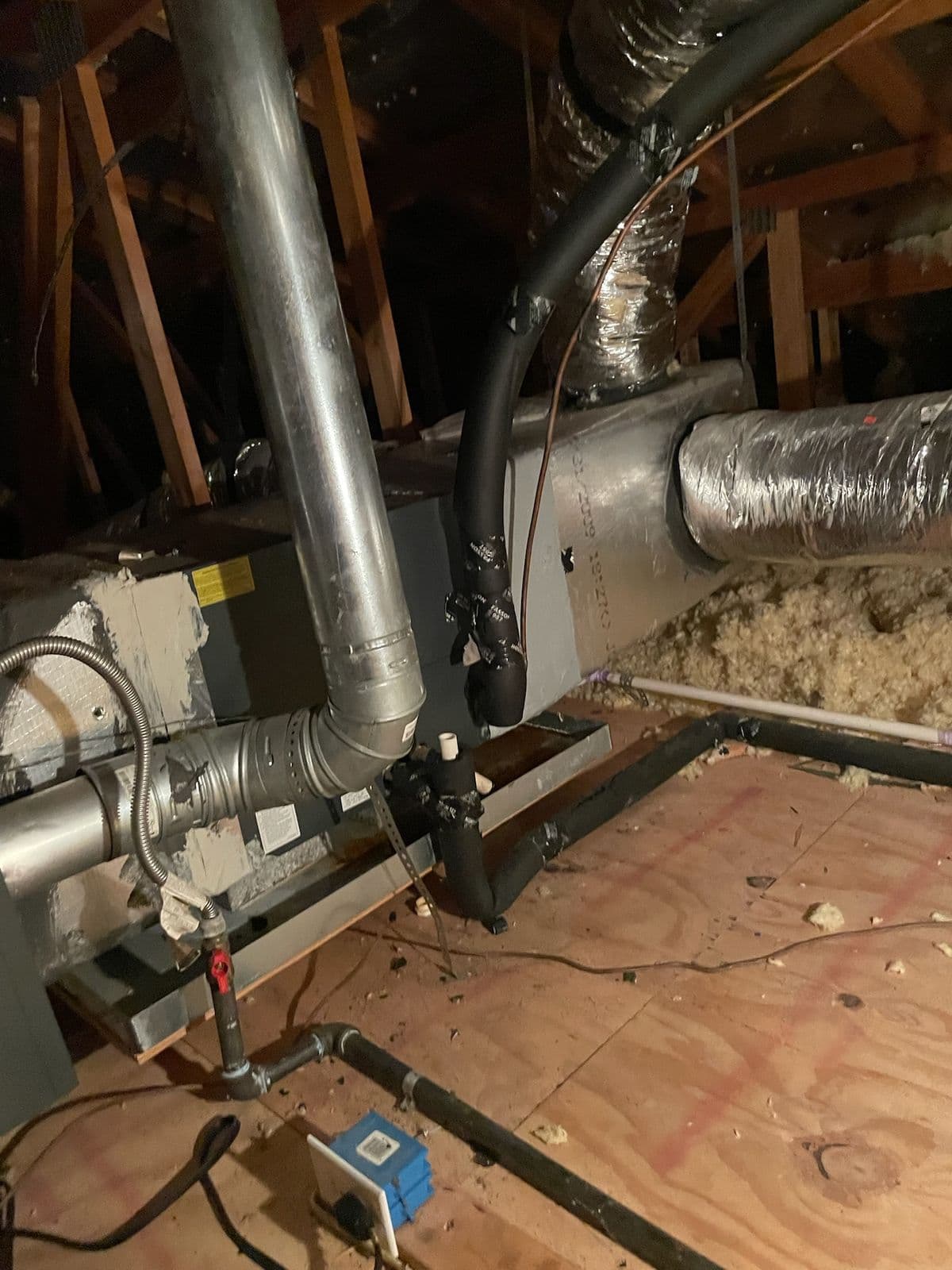 Attic air handler with furnace flue pipe and ductwork serviced by AC American Air in San Antonio