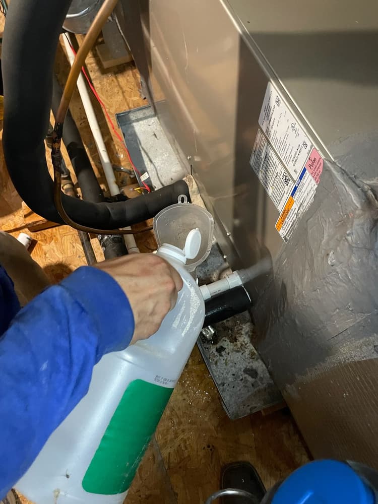 HVAC technician cleaning condensate drain line in attic during San Antonio maintenance visit