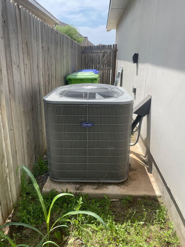New Carrier AC condenser installed in side yard of San Antonio residential home