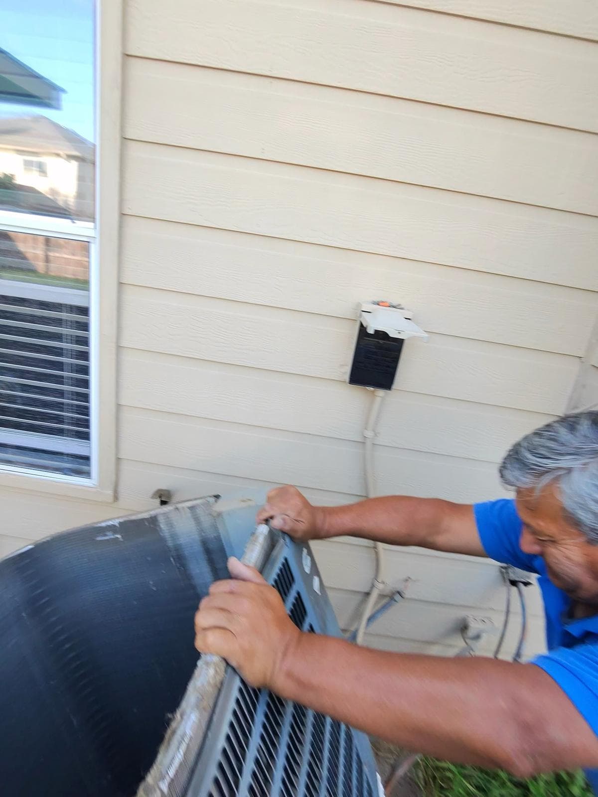 AC American Air technician installing new AC condenser unit at residential home in San Antonio