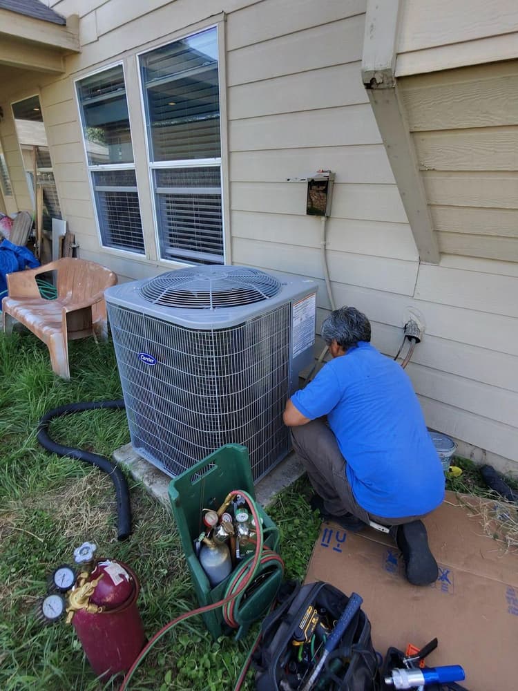 Technician servicing residential AC condenser with refrigerant gauges in San Antonio
